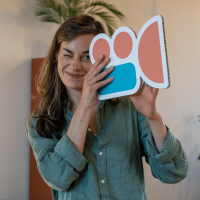 Vrouw knipoogt en houdt een filmcamera-icoon vast.