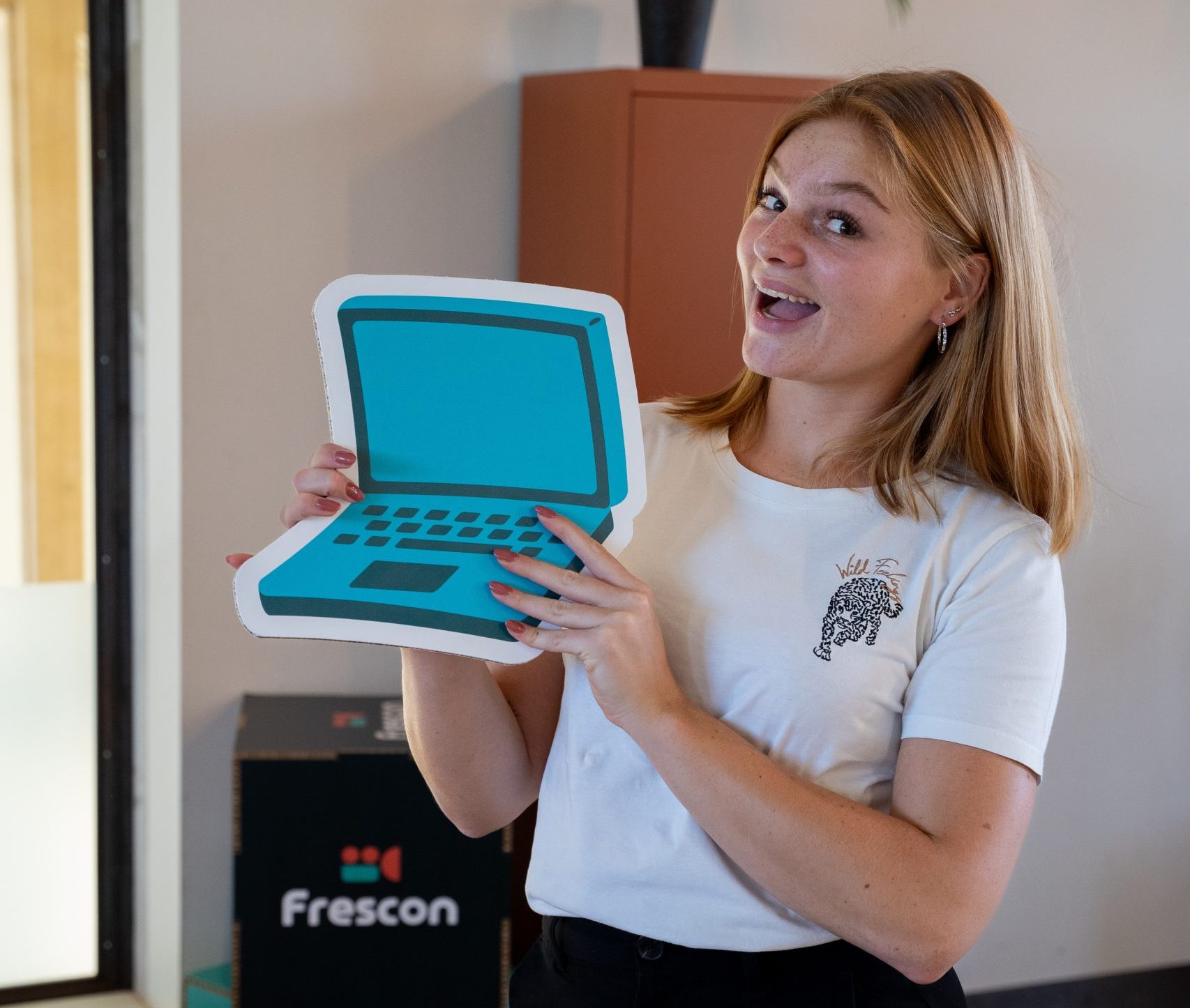 Lachende vrouw houdt blauw laptop-icoon vast.