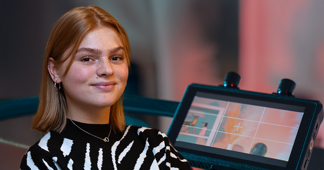 Lieke in zwart-wit gestreepte trui staat voor een camera met monitor.