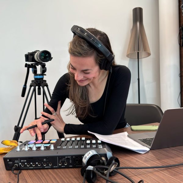 Vrouw bedient audiomixer met koptelefoon op in studio-omgeving.
